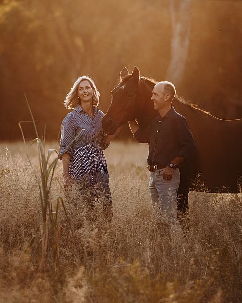 Couple in a paddock with horse at sunset